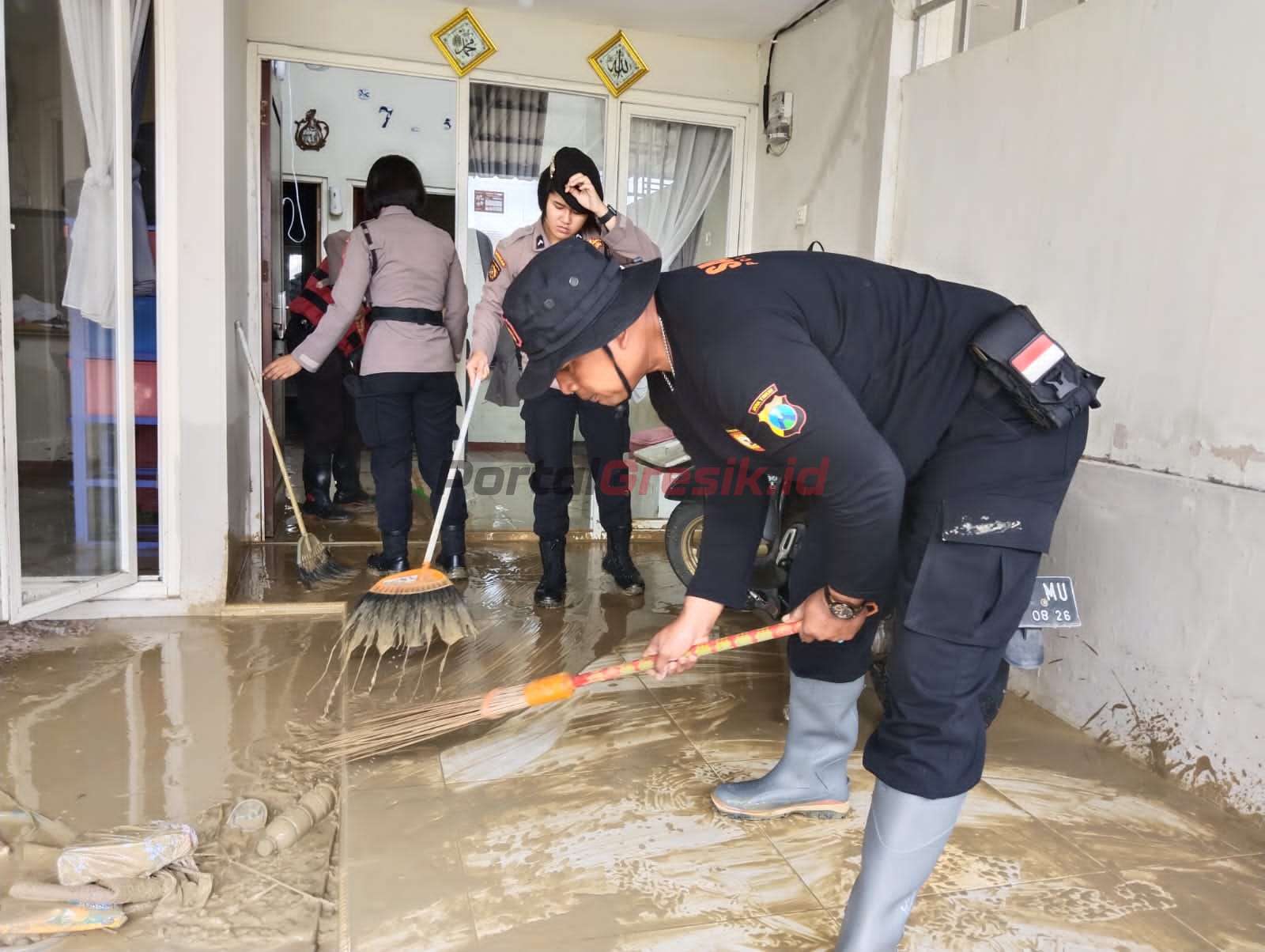 Personel Unit Sat Samapta Polres Gresik saat membantu membersihkan rumah-rumah warga yang terdampak banjir, Rabu (22/2/2023).