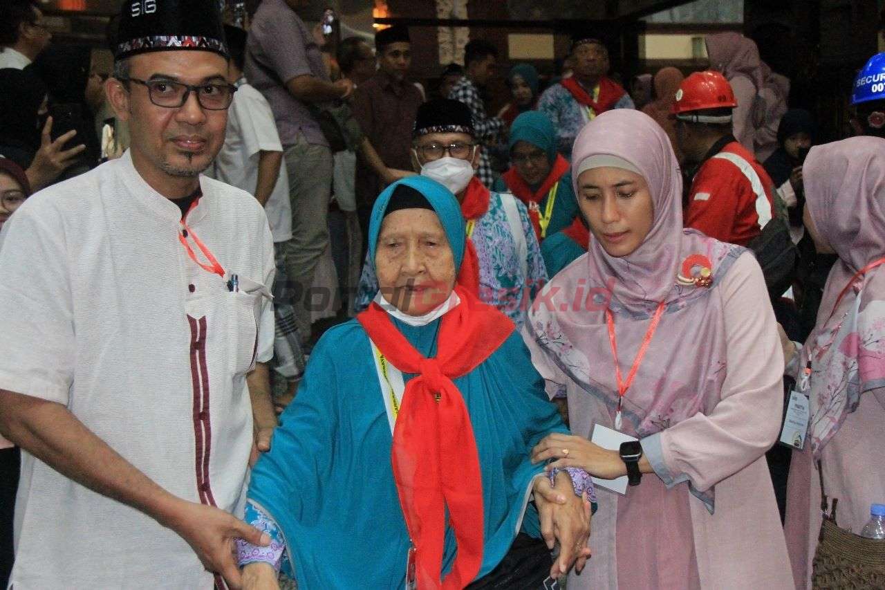 Masmuchibah Syukri Saleh (tengah), jemaah haji tertua (87 tahun) didampingi Panitia Pemberangkatan dan Penjemputan Haji SIG (P3HSIG) saat pemberangkatan menuju Asrama Haji Sukolilo, Surabaya, Selasa (20/6).