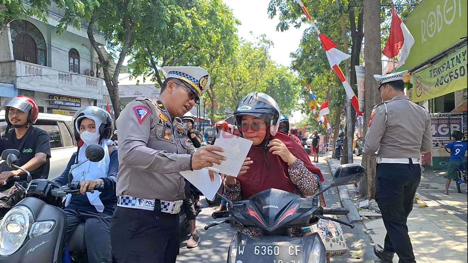 Satlantas Polres Gresik saat membagikan kumpulan soal teori praktik SIM dalam bentuk barcode kepada pengendara