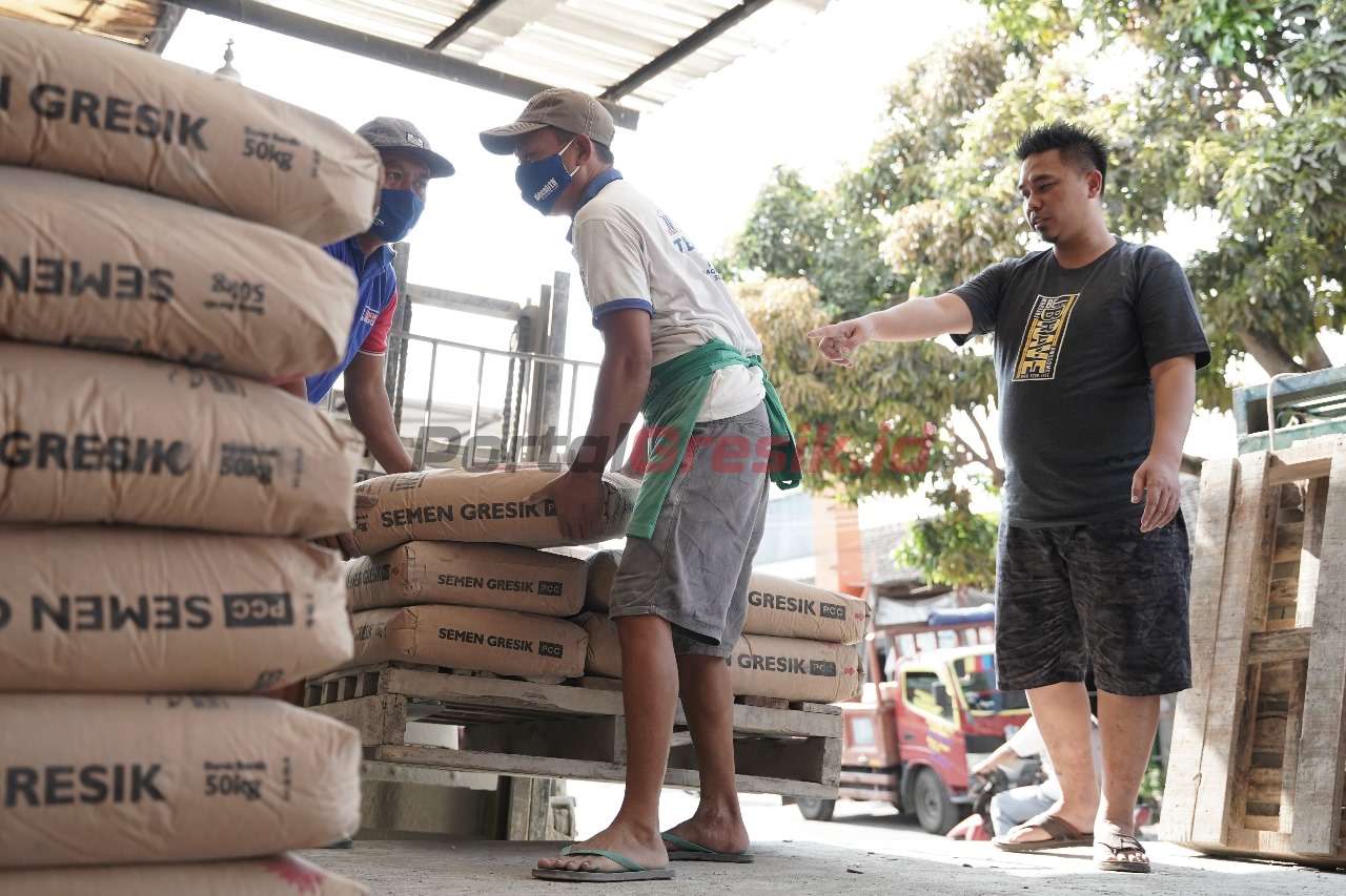 Tri Haryanto (kanan), pemilik toko bangungan Tulung Agung di Klaten, Jawa Tengah, saat mengawasi proses bongkar muat zak Semen Gresik. Dia menjadikan Semen Gresik sebagai pilihan utama dalam penjualan zak semen karena sejak dulu telah teruji kualitasnya.