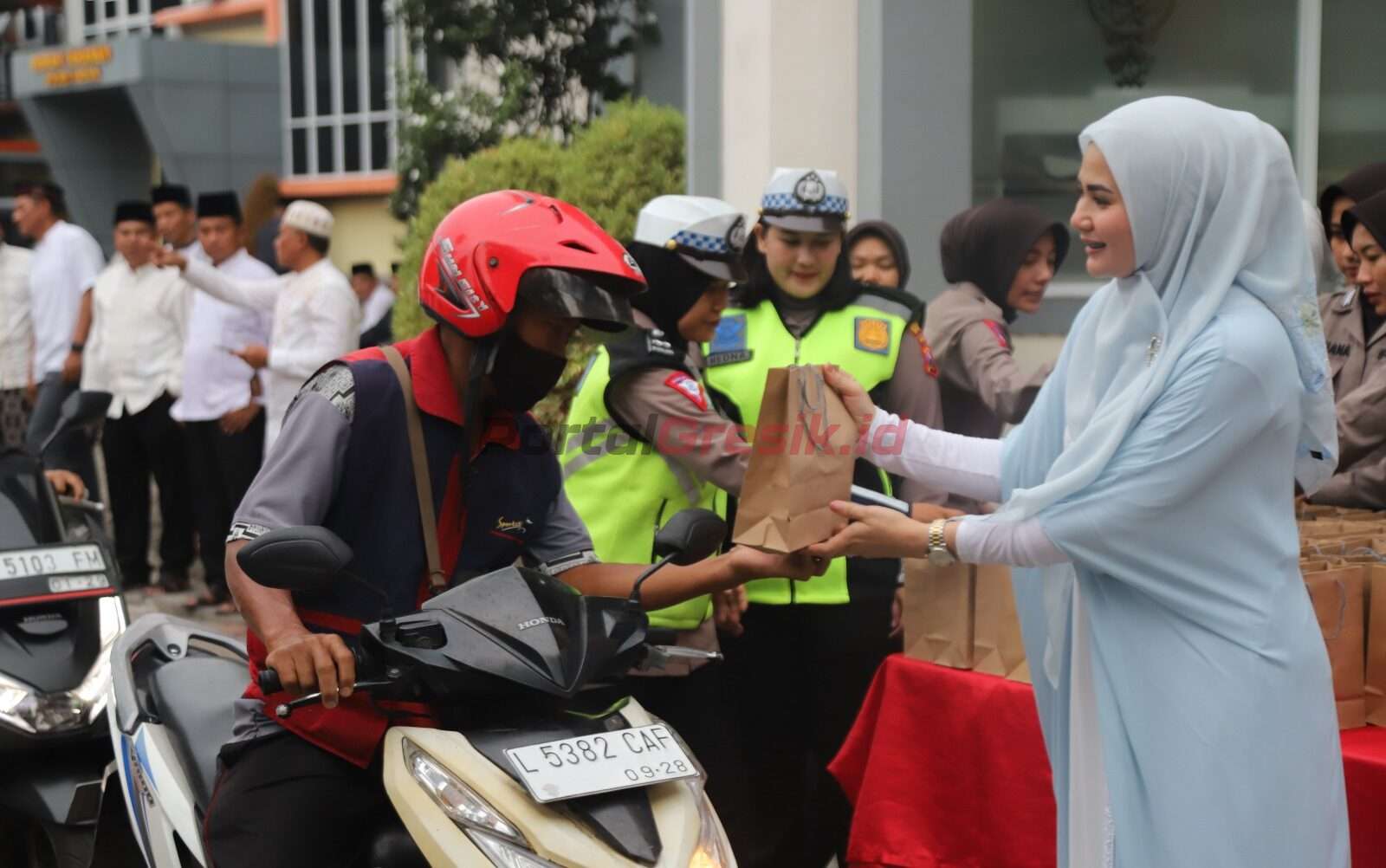 Puluhan Polwan Polres Gresik dan personel Polres Gresik dibantu ibu-ibu Bhayangkari Cabang Gresik membagikan takjil di depan Mapolres Gresik pada hari Kamis (28/3/2024).