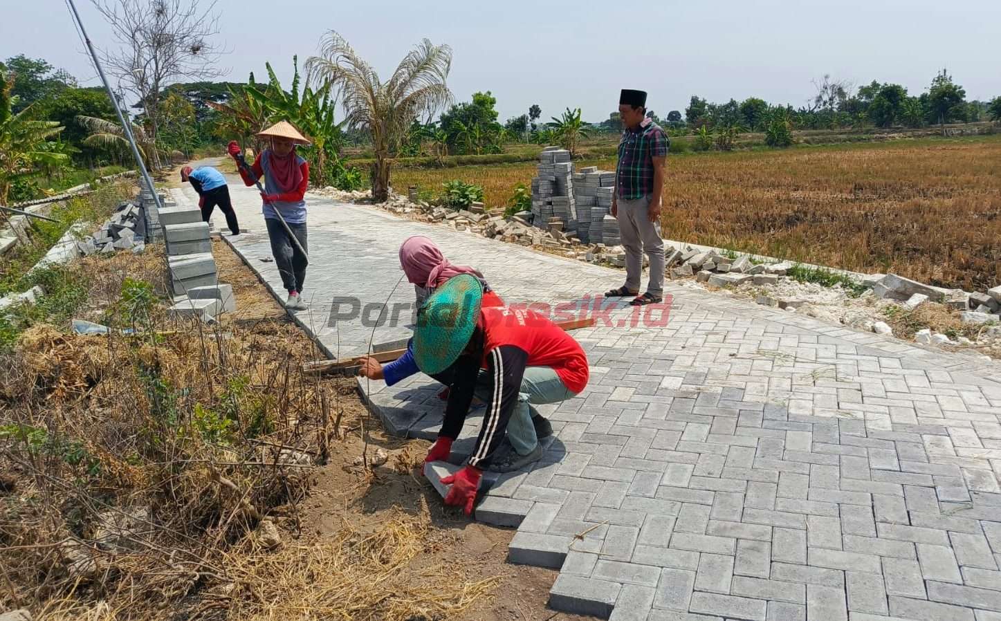 Mansur (berkopyah) Kepala Desa Karangcangkring saat meninjau pengerjaan pavingisasi jalan lingkungan yang juga menjadi akses jalan pertaniaan warga, Kamis (17/10/2024).