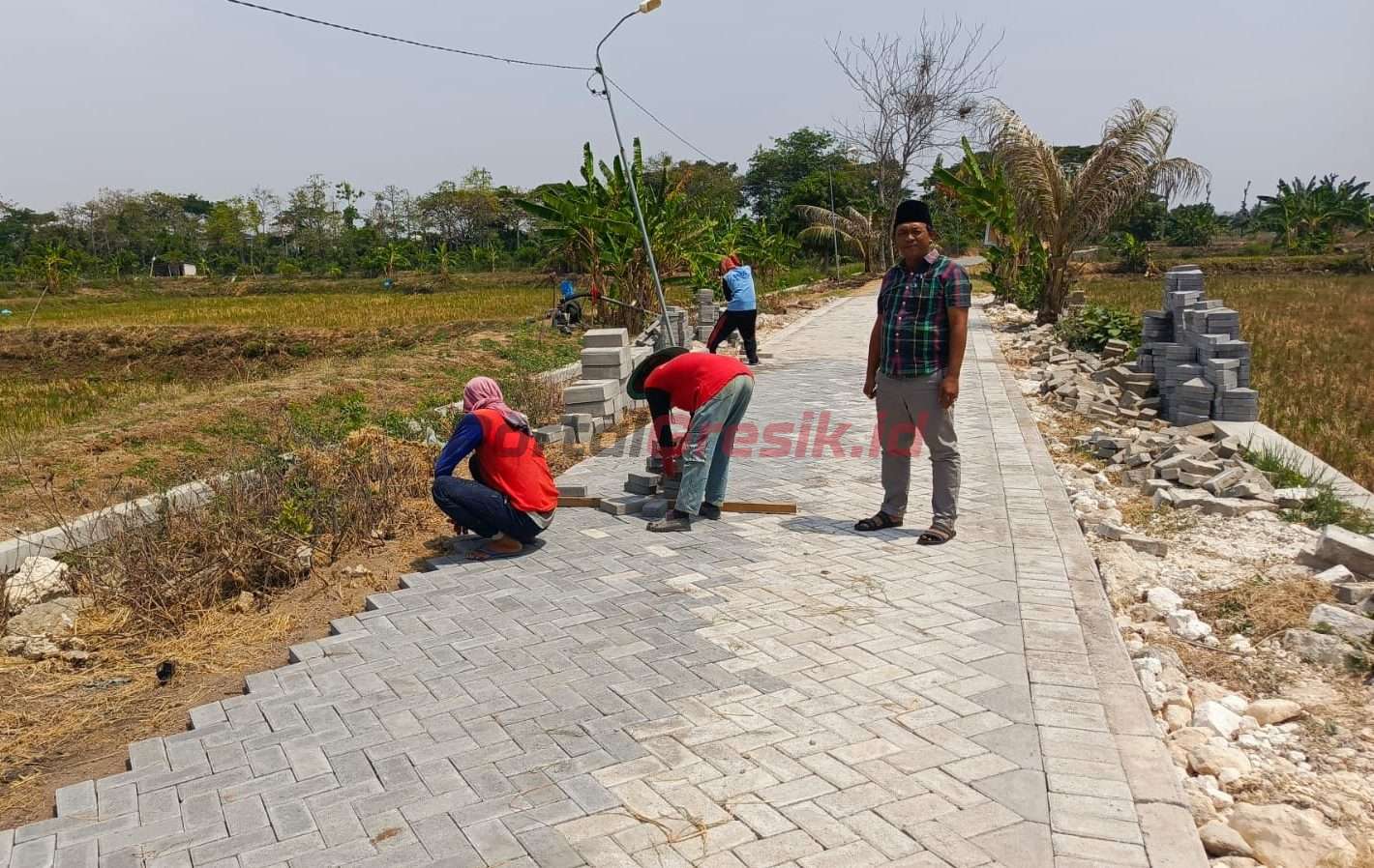 Mansur (berkopyah) Kepala Desa Karangcangkring saat meninjau pengerjaan pavingisasi jalan lingkungan yang juga menjadi akses jalan pertaniaan warga, Kamis (17/10/2024).