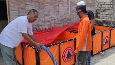Petugas BPBD Kabupaten Gresik didampingi perangkat Desa mengisi tandon air bersih di Desa Boteng Kecamatan Menganti, Jumat (18/10/2024).