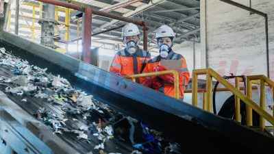 Karyawan SIG melakukan pengecekan material (Refused-Derived Fuel) yang akan dicacah untuk dimanfaatkan menjadi bahan bakar alternatif di area green zone Pabrik Narogong, Jawa Barat.