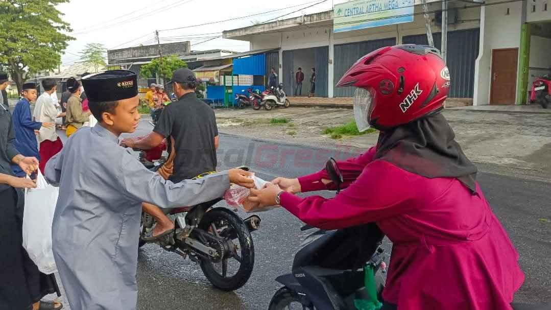 Santri MTs Refah Islami saat berbagi takjil kepada pengguna jalan raya di depan Pondok pesantren Refah Islami Sukorejo Sidayu, Kamis (20/3/2025).
