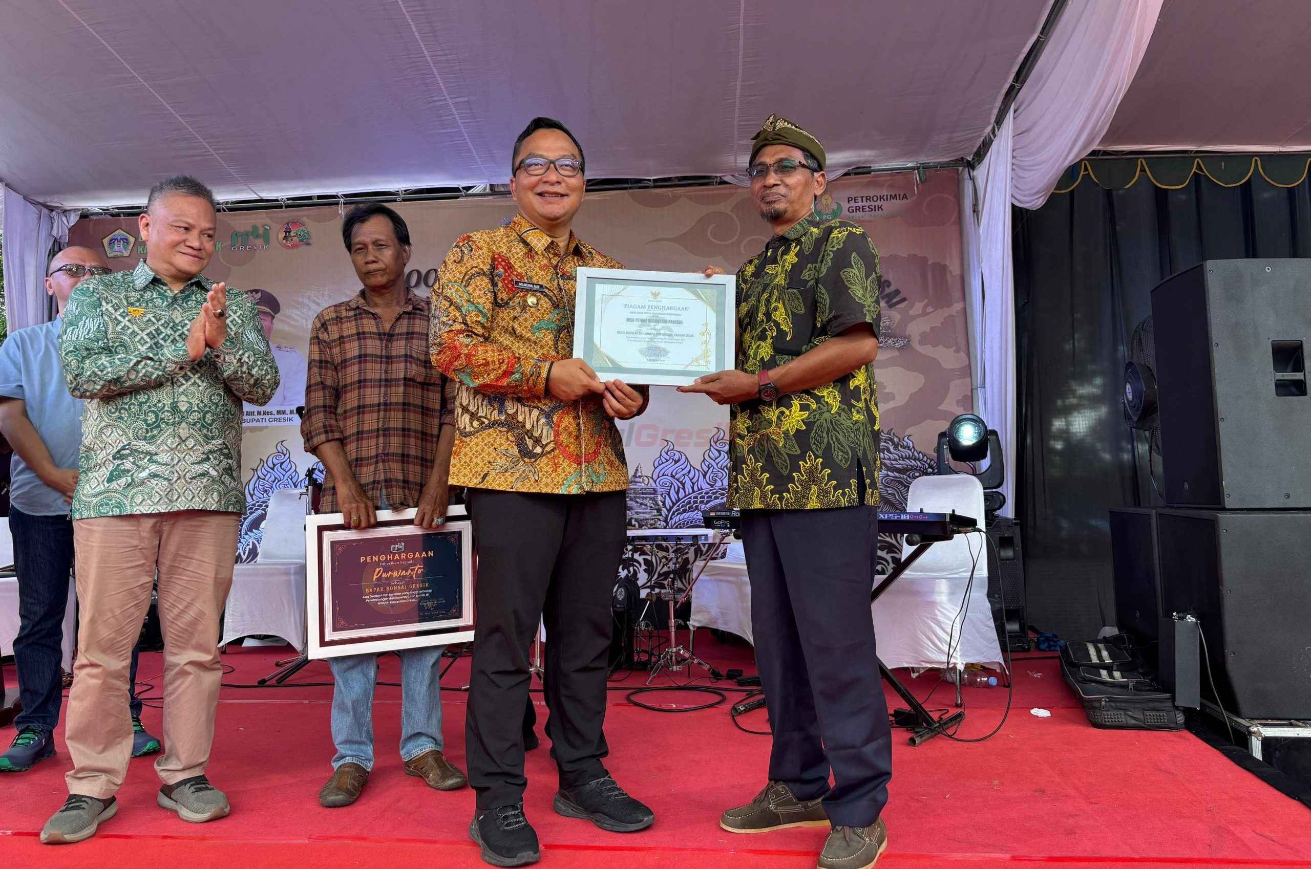 Pemberian piagam oleh Plt Bupati Gresik dr. Asluchul Alif kepada Kepala Desa Petung Muhammad Mas’ud saat acara Pameran dan Kontes Bonsai Nasional di Halaman Kantor Bupati Gresik, Jumat (9/5/2025).