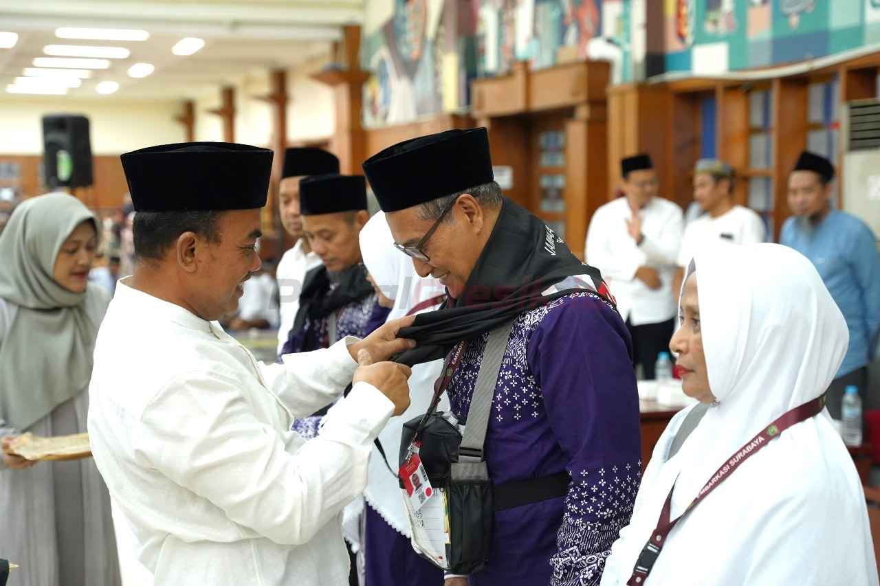 General Manager of CSR SIG, Edy Saraya (kiri) menyematkan syal kepada perwakilan jemaah haji Gresik sebagai tanda pelepasan jemaah haji ke tanah suci di Wisma A. Yani SIG, Kabupaten Gresik, Jawa Timur, pada Sabtu (3/5/2025).