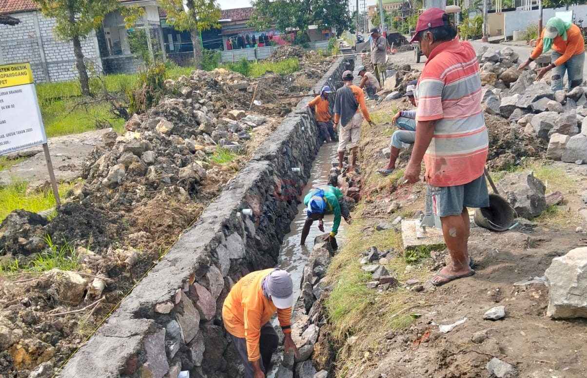 Pekerja saat melakukan pekerjaan pembangunan saluran air di Warga Desa Dapet, Kecamatan Balongpanggang, Kabupaten Gresik,