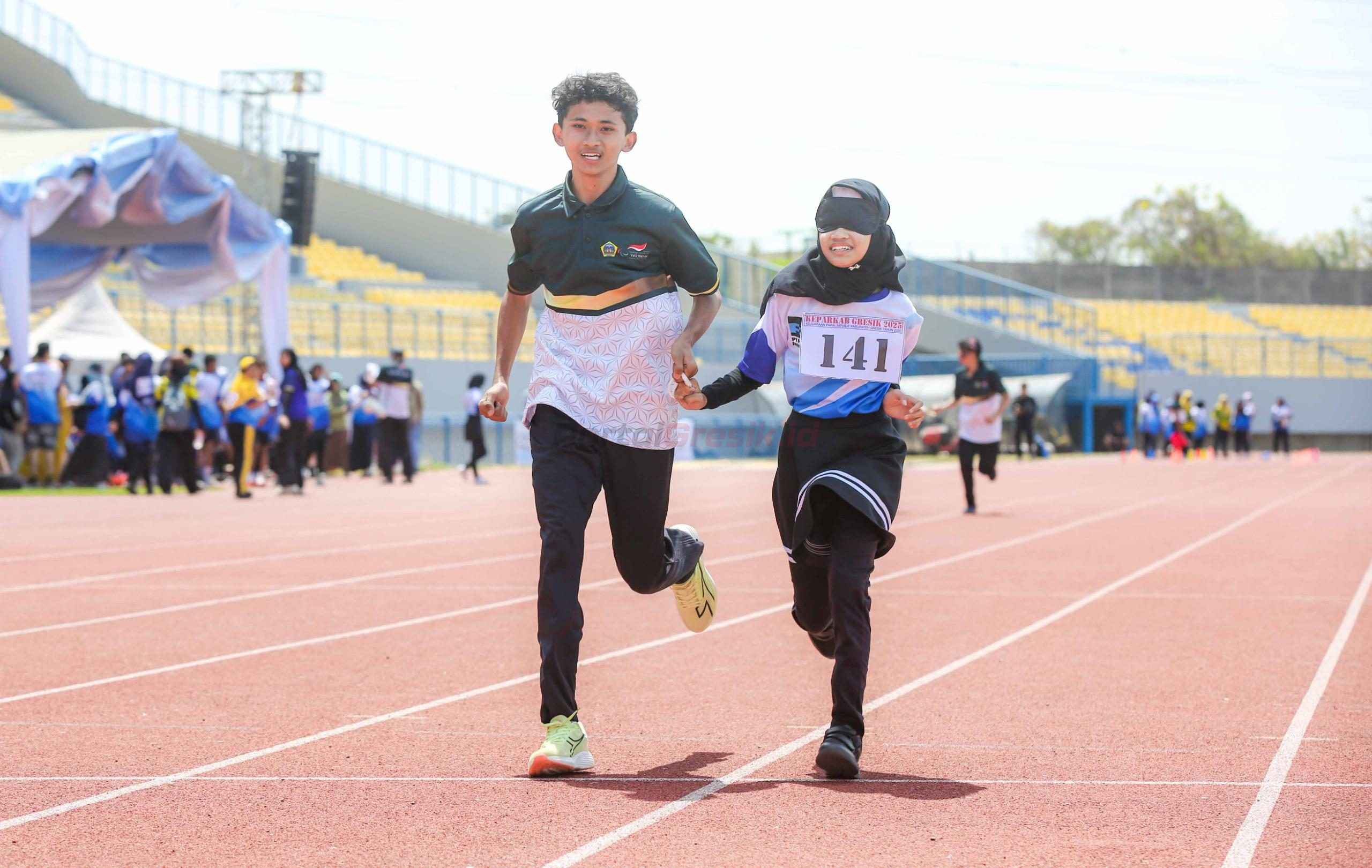 Atlet disabilitas netra berlari didampingi oleh guide runner yang menunjukan semangat dan kekompakan untuk mencapai garis finish (13/8).