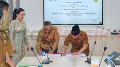 Direktur Utama SIG, Indrieffouny Indra (tengah) dan Bupati Bekasi, Ade Kuswara Kunang (kanan) menandatangani Kesepakatan Bersama tentang Peningkatan dan Pengembangan Kualitas Pembangunan di Kabupaten Bekasi, disaksikan oleh Ketua Dewan Penasihat Bupati Bekasi sekaligus Anggota Komisi VI DPR RI, Rieke Diah Pitaloka di Kantor Bupati Bekasi pada Senin (25/8/2025).