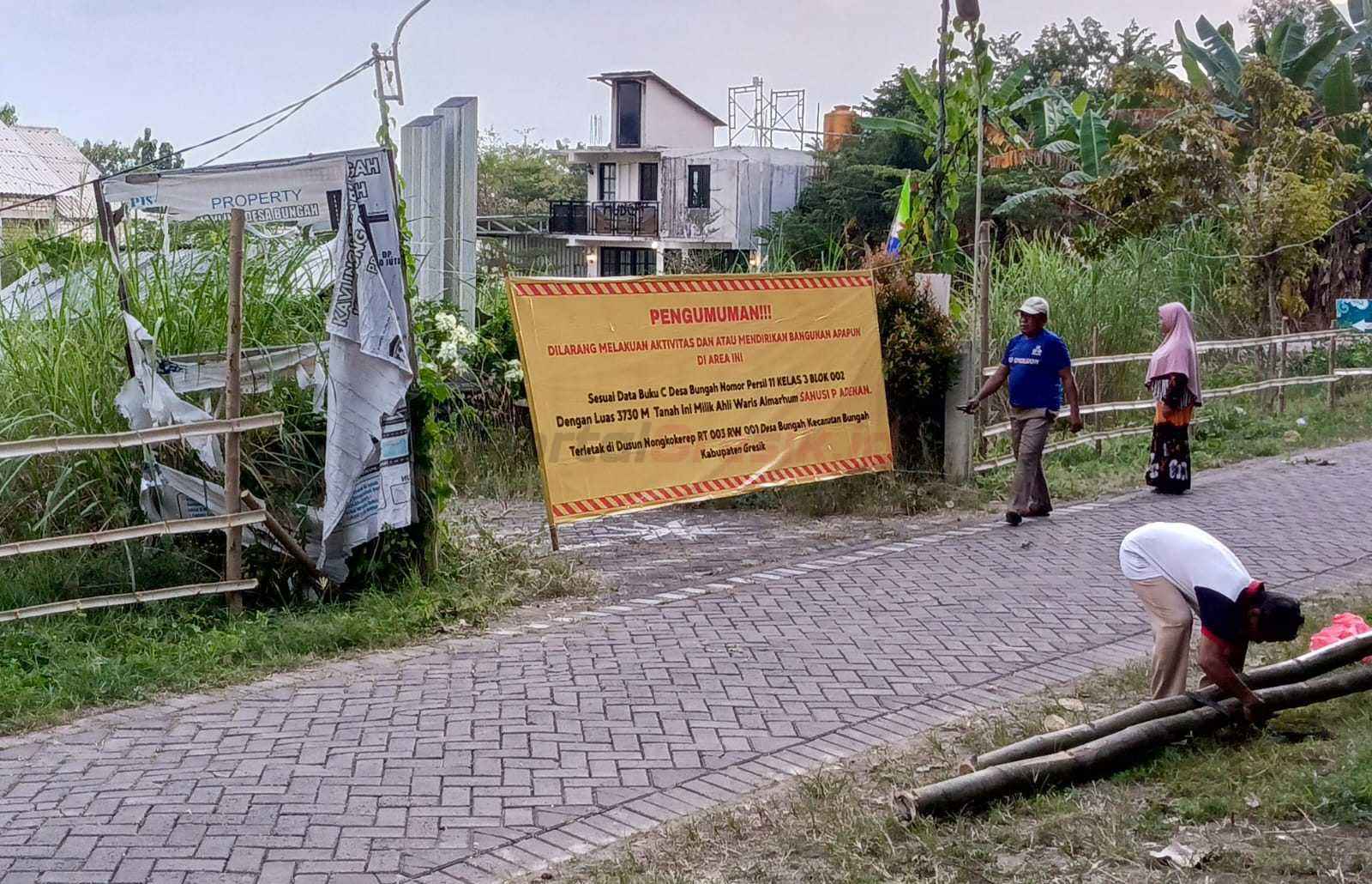 Ahli Waris pemilik tanah atas nama Sanusi P Adenan seluas 3.740 meter yang berlokasi di Dusun Nongkokerep RT 03 RW 01, Desa Bungah, Kecamatan Bungah saat memasang spanduk peringatan di area tanah yang berisi larangan mendirikan bangunan apapun, Minggu (3/8/2025).